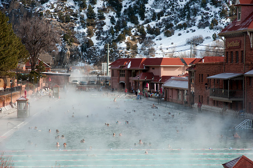 Glenwood Springs, United States - December 28, 2013: Glenwood Hot Springs in Winter - The historic Glenwood Hot Springs pool is 104 degrees year round, so on a cold winter morning, with snow covered moutains, steam rises off the pool's surface