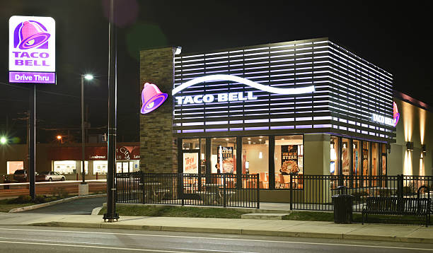 Taco Bell Late Night Hours Dayton, Ohio, USA - December 13, 2015: Taco Bell Restaurant, shown here at night in its newer 2013 purple design, has recently announced its implementation of exclusively using cage-free eggs in its 6000 US locations by the end of 2016.   dayton ohio photos stock pictures, royalty-free photos & images