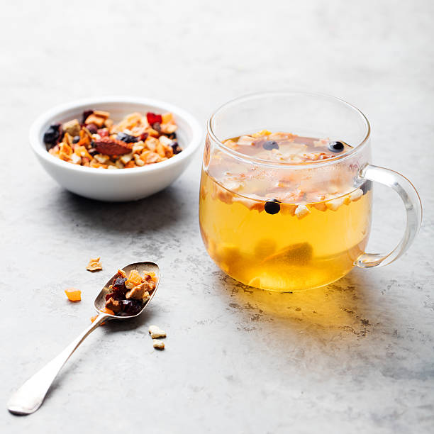 Fruit tea, dried fruits and spices, in transparent cup on a grey stone background