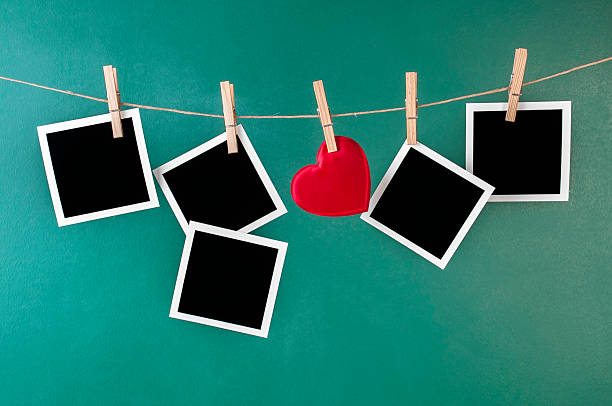 Red heart with sheet of photo papers hanging on the clothesline