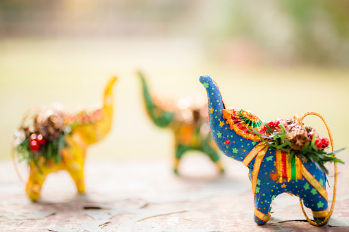 Handmade Christmas ornaments from India. Beautiful, brightly colored designs in various shapes.  Herd of elephants pictured. Focus on elephant in foreground. Merry Christmas!  