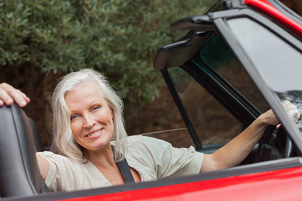 istock Smiling mature woman posing in red convertible 501260319