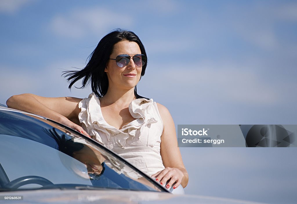 Stylish girl and car Beautiful young girl standing near the car against the sky Adult Stock Photo