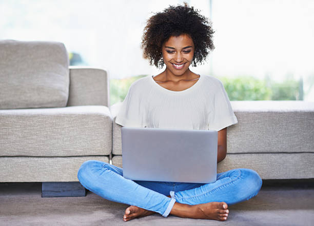Staying connected is just so easy nowadays Shot of a young woman using a laptop while relaxing at homehttp://195.154.178.81/DATA/i_collage/pi/shoots/783516.jpg cross legged stock pictures, royalty-free photos & images