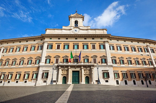 Palazzo Montecitoro, seat of the Italian Chamber of Deputies, is a parliament building in Rome, Italy. Originally designed by Bernini, the baroque palace architecture was completed by Carlo Fontana, who added the bell gable above the facade main entrance. The multi-story built structure is a center for government politics and policy.