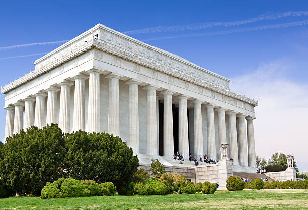 Lincoln Monument, Washington DC, USA. Green grass, bushes, trees, tourists resting on the steps and vivid blue clear sky with some clouds are in the image. Canon EF 24-105mm/4L IS USM Lens.