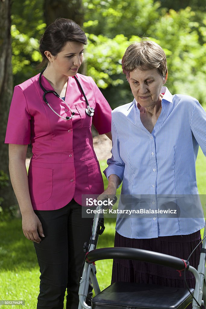 Woman with walker in garden Nurse and woman with walker in garden Adult Stock Photo