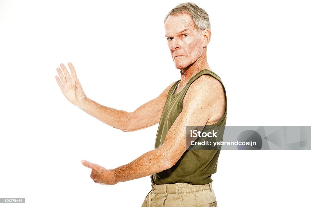 Athletic good looking senior man casual summer dressed. Athletic good looking senior man casual  summer dressed against white wall. Working out his muscles. Happy, funny and characteristic. Isolated. Studio shot. Active Seniors Stock Photo
