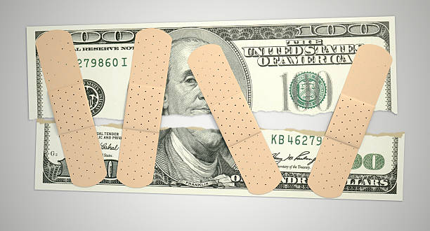 Nursed Torn US Dollar A concept picture of a regular one hundred dollar note torn in two length ways and held together by medical plasters on an isolated background desecrate stock pictures, royalty-free photos & images