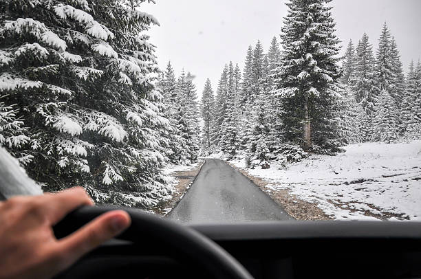Man Driving in a Snow through mountain forest stock photo