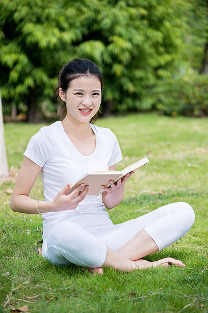 istock Young woman reading a book in park 501286398