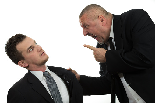 Businessman screaming and fighting at a young colleague isolated on white