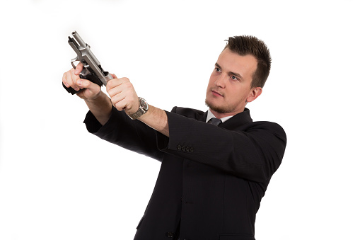 Young man pointing a gun isolated on white background