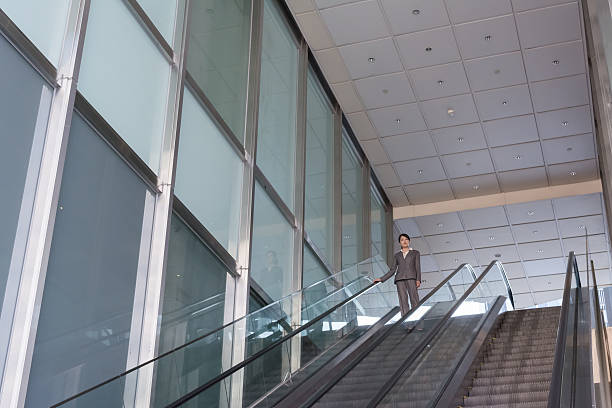 istock Asian business woman stand at escalator 501293301