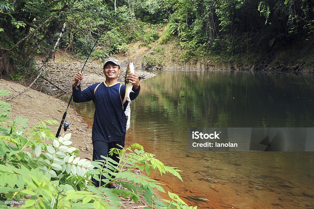 angler with his catch at tropical river in the forest Tranquil tropical river in the forest with angler in action Activity Stock Photo