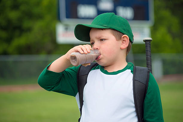 Child baseball player drinking chocolate milk stock photo