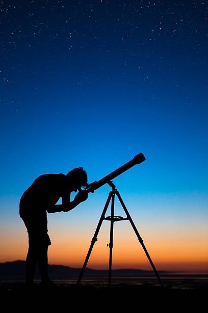 niño en una noche clara mirando a través del telescopio una - mirar a través fotografías e imágenes de stock