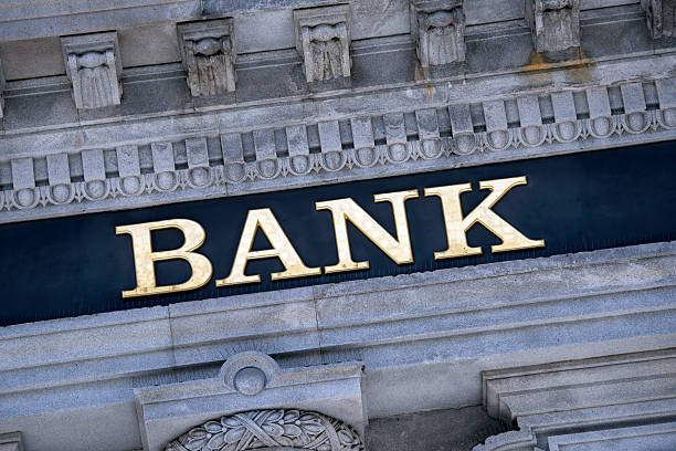 Signage above the entrance to a modern generic bank building made of exposed concrete and reflective glass at night time - 3D render