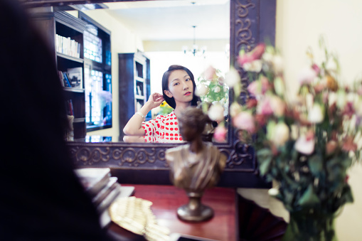 young chinese girl, standing in front of her dressing table, combing his hair