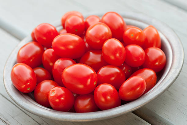 kleinen traditionellen tomaten in keramische bowl - cherry tomato image raw colors stock-fotos und bilder