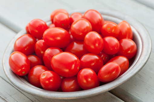 Many red tomatoes in wooden box isolated on white background