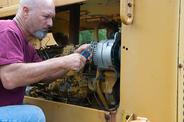 istock Man using pliars to install new alternator on roadgrader 501337419