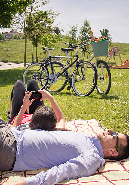 istock Girl using smartphone lying over man on the park 501340129