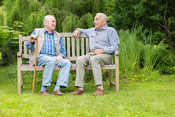 istock Two senior men sitting on bench in the park 501340789