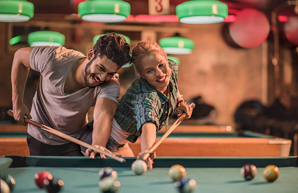 istock Playful couple trying to hit the same pool ball. 501358842