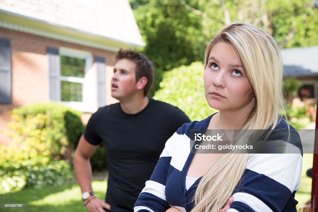 Young woman rolls her eyes A young couple having a disagreement.  The young lady rolls her eyes at the young man who seems distracted and confused in the background. Adult Stock Photo