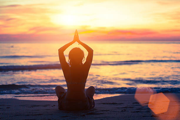 istock Young girl in yoga pose sitting on beach during sunset. 501368508