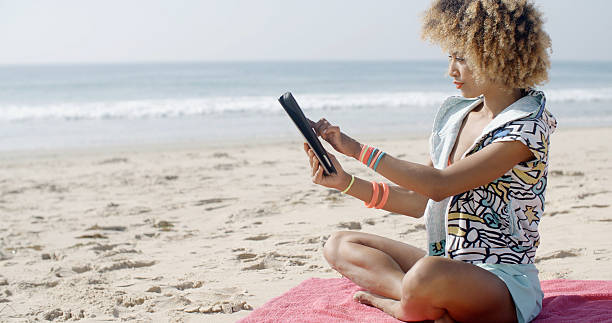 istock Woman Uses Touchpad Tablet On The Beach 501397604