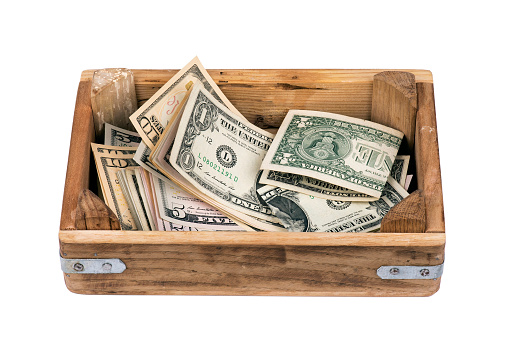 Various US Dollars in Wooden Container isolated on white Background.
