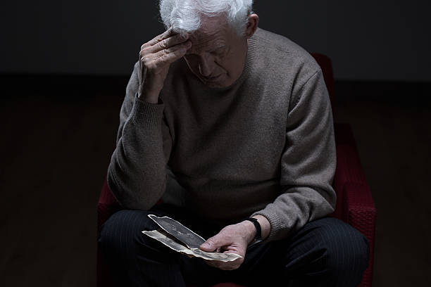 Elder depressed man watching old photos of his family