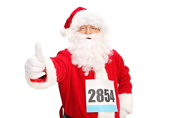 Santa Claus with a race number on his chest giving a thumb up and looking at the camera isolated on white background