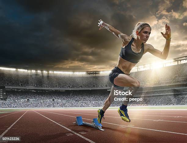 Woman Sprinter In Mid Action Bursting From Blocks During Race Stock Photo - Download Image Now