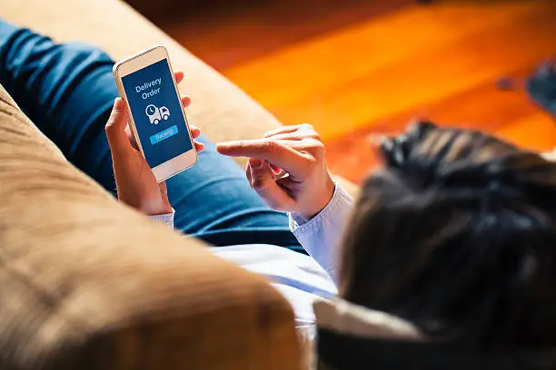 Delivery order message in a mobile screen. Woman reading it at home.