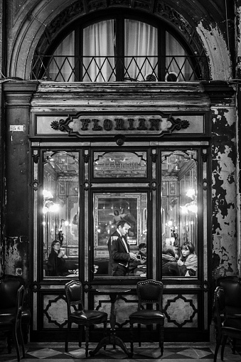 Venice, Italy - December 9, 2015: Monochrome image of a waiter serving tourists sitting in Caffe Florian, Venice, Italy during the 2015 Christmas period. 
