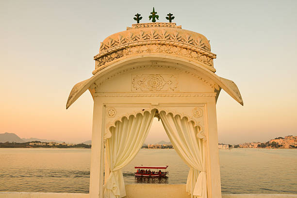 Boat Ride on Lake Pichola Seen in Gazebo, India This is a horizontal, selective focus shot of a boat ride on Lake Pichola seen through a gazebo. This was shot at dusk from Jag Mandir Island in Udaipur, India. The lake shore is seen beyond.  udaipur stock pictures, royalty-free photos & images