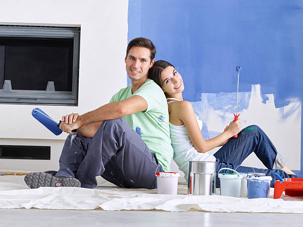 istock Couple sitting back to back with roller brushes in hand 501434810
