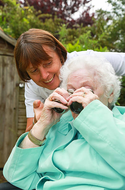 istock Careworker nurse caring for an elderly client playing with binoculars 501442419