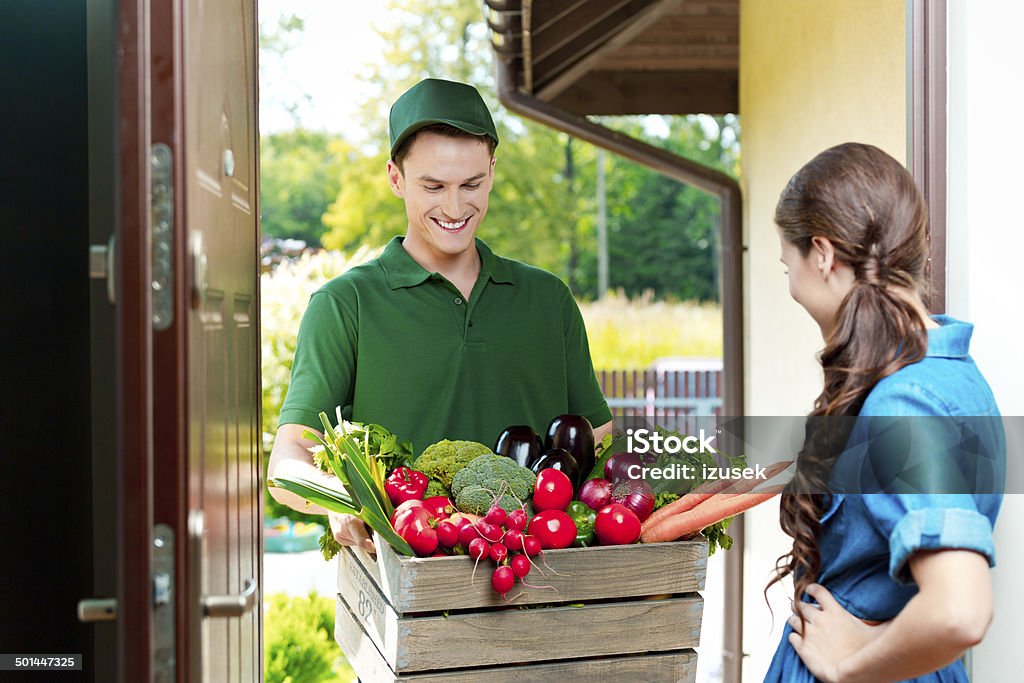 Delivery man with organic food Delivery man delivering to home box with organic food, talking with female customer. Delivering Stock Photo