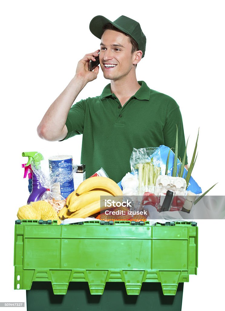 Delivery man Delivery man delivering box with groceries, talking on phone. Studio shot, white background. Delivering Stock Photo