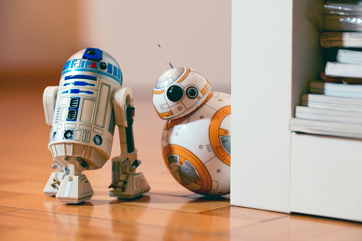 istanbul, Turkey - December 12, 2015: BB-8 and R2-D2 toys hiding behind a bookshelf. They are droids of Star Wars movie appearing in The Force Awakens episode. BB-8 toy is produced by Sphero for Lucas Film.