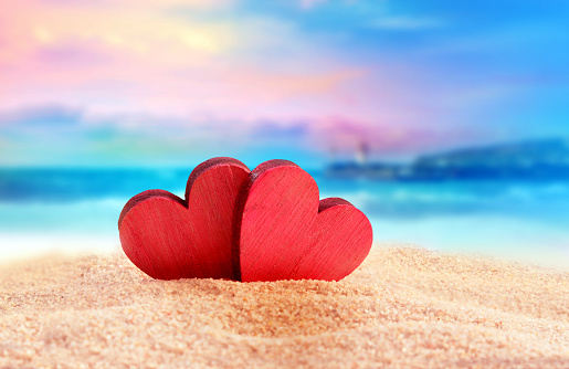 Two wooden red hearts on the summer beach