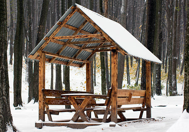 wooden arbour covered with white snow in the autumn forest