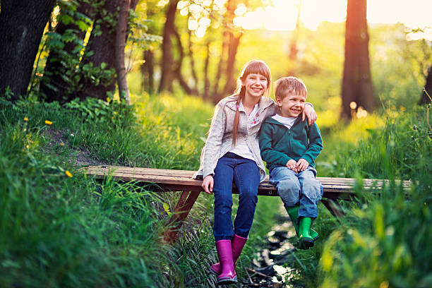 istock Brother and sister sitting on bridge in forest 501477736