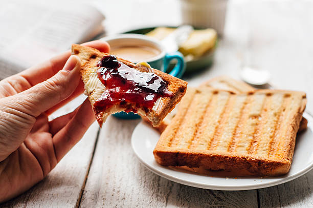 frau hand essen toast für frühstück - toast preserves breakfast bread stock-fotos und bilder