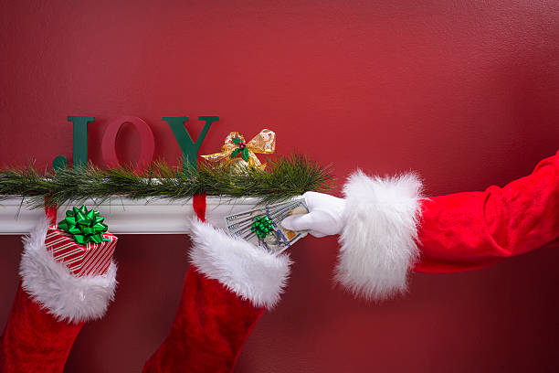 istock Santa's hand placing new $100 bills into Christmas Stockings 501481268