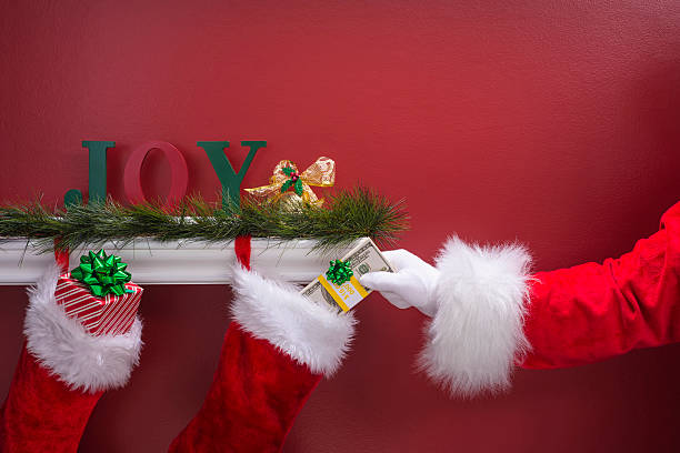 istock Santa's hand placing a bundle of $100 into Christmas Stockings 501481792